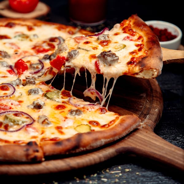 A slice of Mike's Pizza Deli Station's Italian pizza with melted cheese, beef, onions, and peppers.